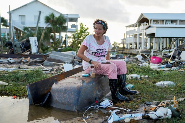 A woman in Horseshoe Beach, Florida, sits on an upturned bathtub after a hurricane destroyed her home.