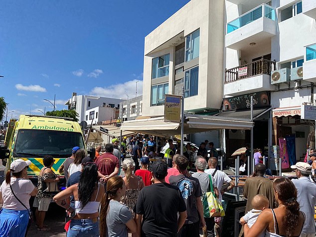 A crowd surrounds the scene as paramedics work to evacuate the injured