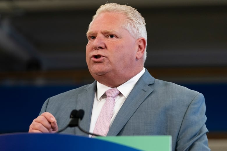 A man speaks at a press conference inside a high school auto shop classroom.