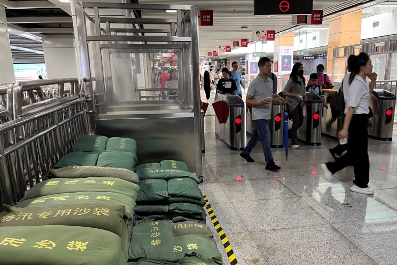 Commuters walk past sandbags at a subway station.