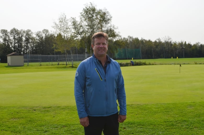 A man stands on a golf course.