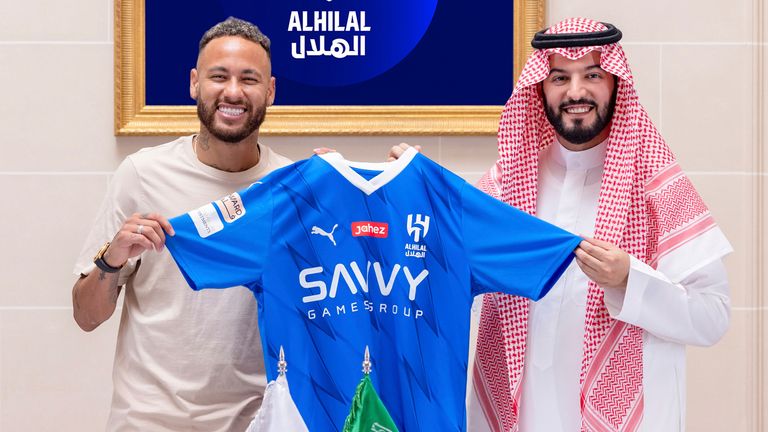 In this photo provided Al Hilal club media center, Neymar holds a Al Hilal shirt after signing with Chairman of the Board of Directors of Al Hilal, Fahad Bin Saad Bin Nafel, in Paris, France, Tuesday, Aug. 15, 2023. (Al Hilal Club Media Center via AP)