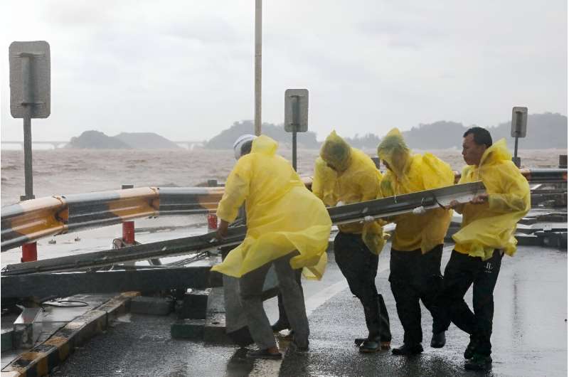 Workers in the coastal Chinese city of Zhuhai moved metal railings during the storm from the roads, and cleared sand whipped fro