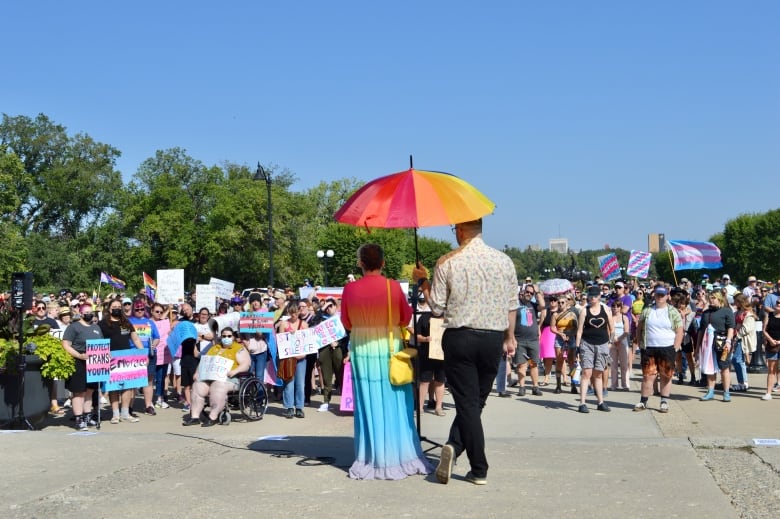 Woman in a colorful dress adressing a crowd of a few hundred people 