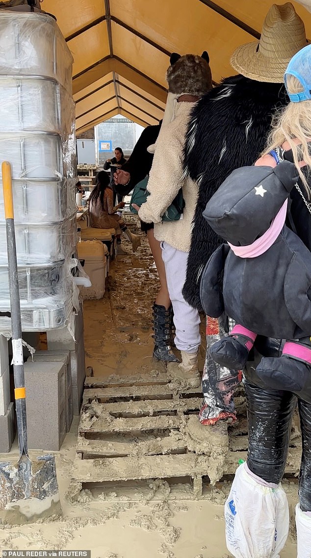 People use plastic bags to cover their shoes as others are seen with their boots covered in mud