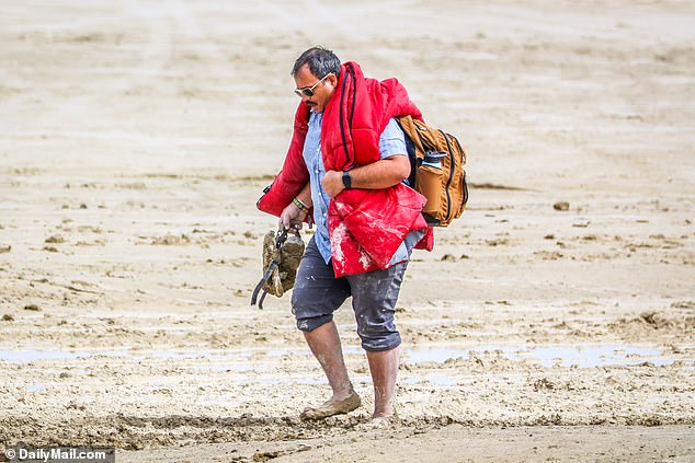 A man can be seen trying to walk out of the site with his belongings including a sleeping bag