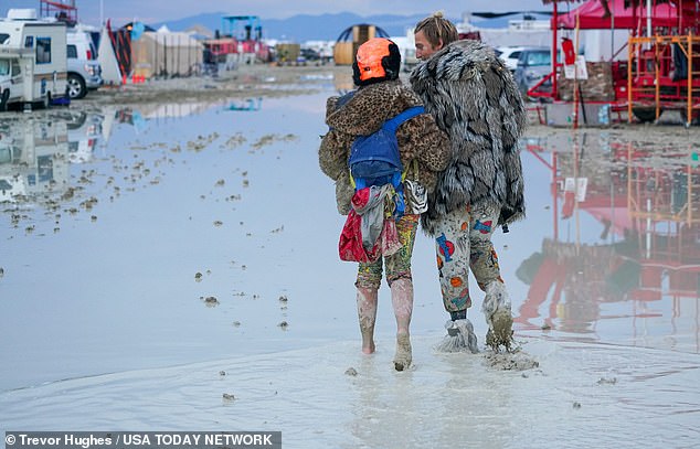 Dub Kitty and Ben Joos, of Idaho and Nevada, respectively, walk through the mud at Burning Man  site