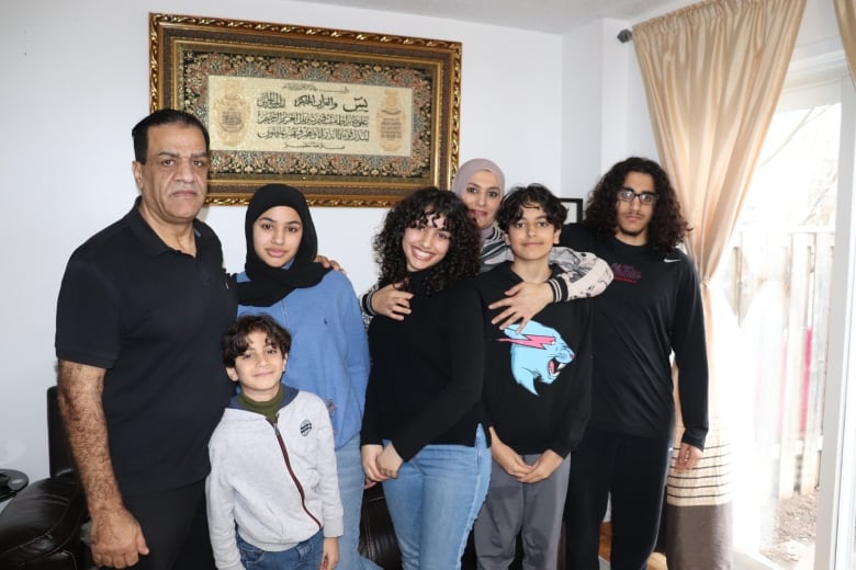 A family poses in front of a white wall. 