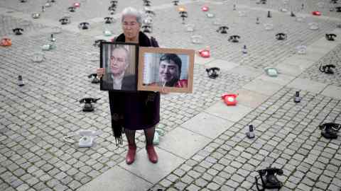 Fadwa Mahmoud holds portraits of her son and husband, who disappeared in 2012, in Berlin, Germany