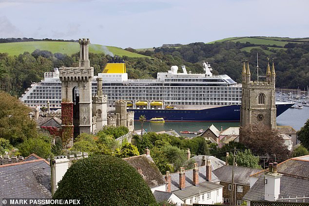 The town of about 2,200 residents offers various shops and eateries for day trip tourists to enjoy, as well as several historic buildings. The massive cruise ship Spirit of Adventure looked out of place in the tiny town as it towered over St Fimbarrus (right), Fowey's parish church and Place House's grade I listed tower (left), on Friday