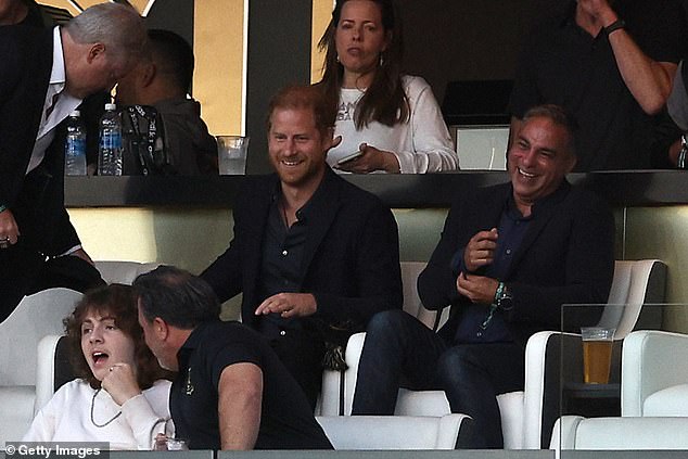 Harry is pictured taking his seat at the game on Sunday night