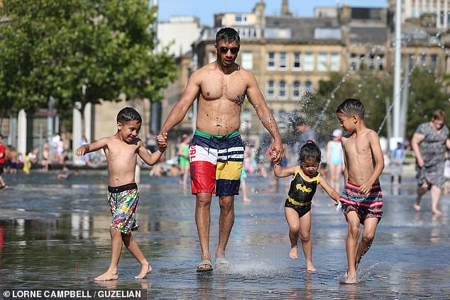 A family enjoys the warm weather in Bradford, West Yorkshire, on Sunday, with temps in the UK set to climb into the mid 30s this week