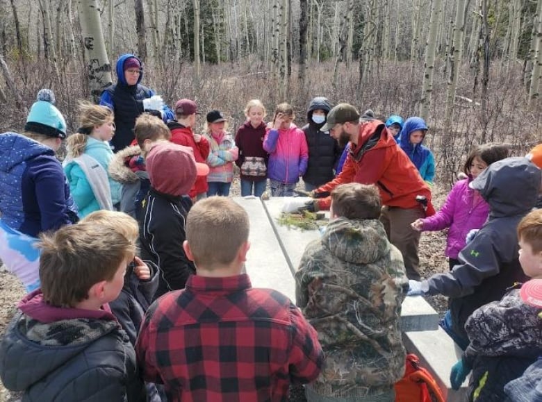 Students in warm clothing gather around a picnic table.