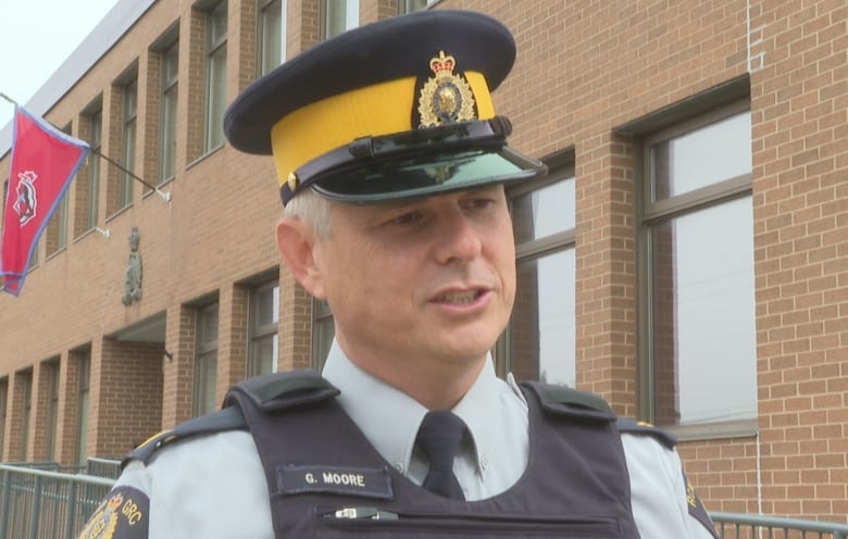 Man in RCMP uniform in front of a brick building.