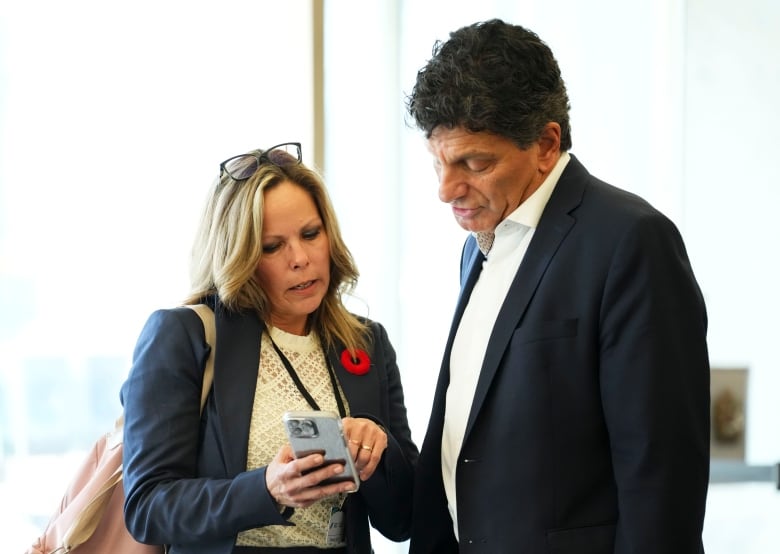 A woman shows a man something on her phone.