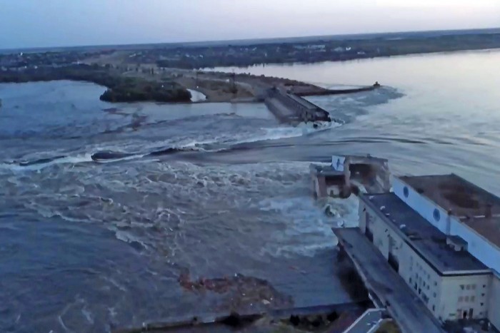 Water breaks through a dam destroyed by Russian forces