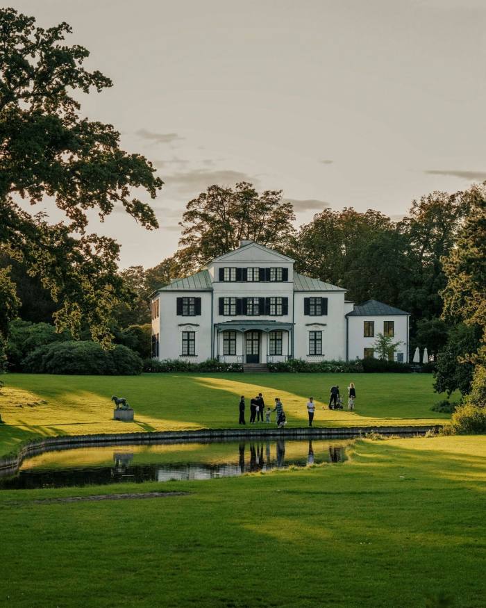 The Øregaard Museum: a white and brown mansion in a park, with lawns and a pond in front of it