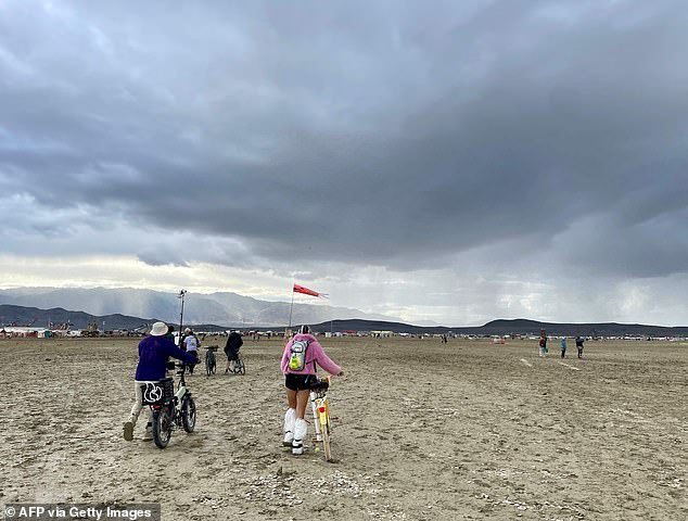 Attendees walk through a muddy desert plain on Monday