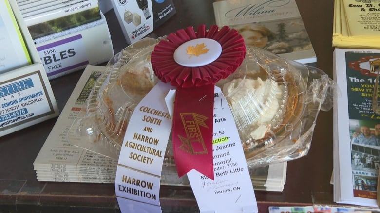 A pie in a plastic container with a ribbon that says "first" on it.