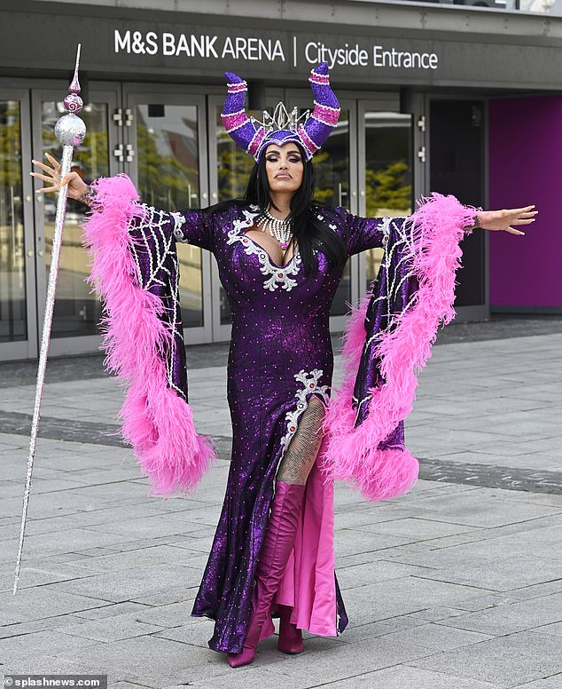 Bold look: Getting into character, Katie put on a busty display in a dazzling purple gown with a daring side split and huge pink waterfall ruffled sleeves