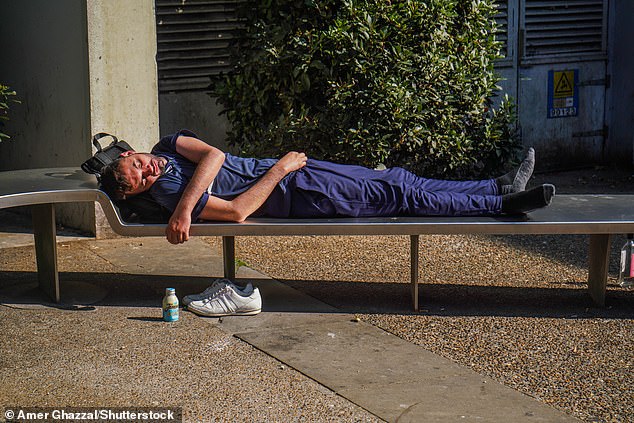 A man sleeps on a bench in London in the bright sunshine today as the heatwave continues