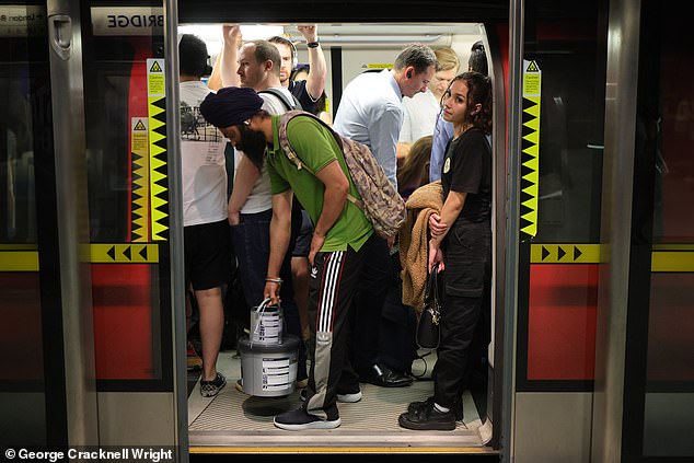 Commuters pack on to a hot Jubilee line Underground train at London Bridge station today