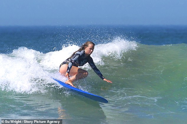 A surfer makes the most of the warm weather in the water off Polzeath in Cornwall today