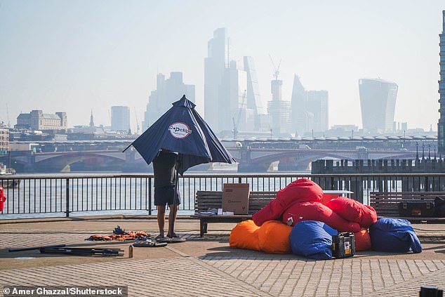 A man adjusts a parasol on the Southbank of the River Thames in London this morning