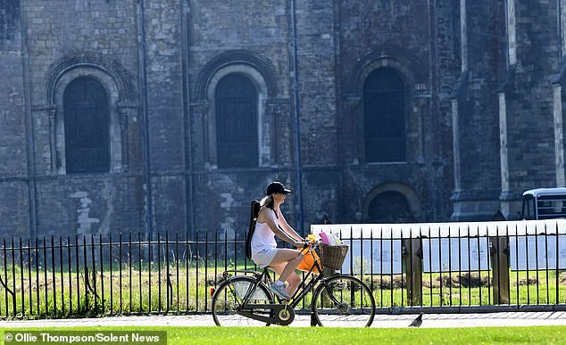 A cyclist enjoys a warm morning ride in the grounds of Winchester Cathedral today