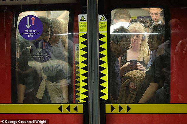 Commuters pack on to a hot Jubilee line Underground train at London Bridge station today