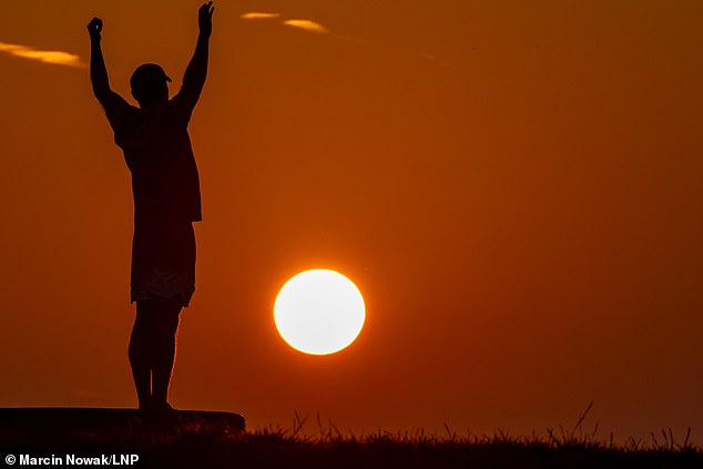 A person watches the sunrise at Primrose Hill in North London this morning