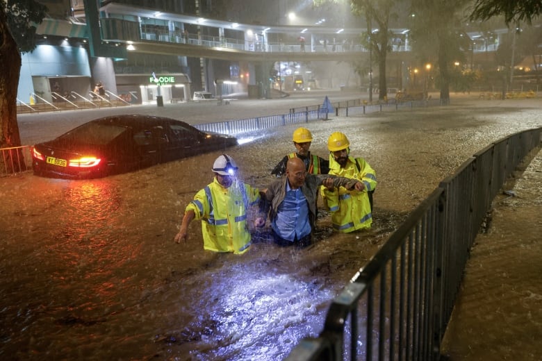 Workers assist a driver who became stranded amid flooding caused by intense rainfall in Hong Kong.