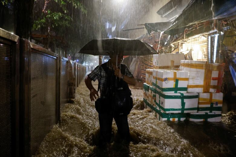 A man carrying an umbrella wades through a flooded area in Hong Kong.