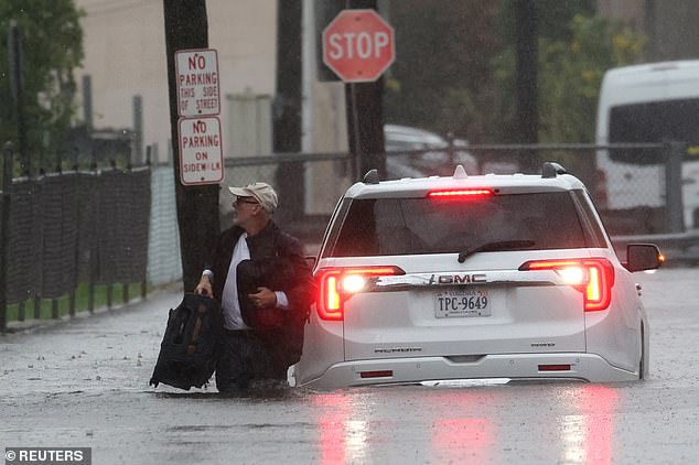 A person walks away from his vehicle after it got stuck in high water on the Prospect Expressway