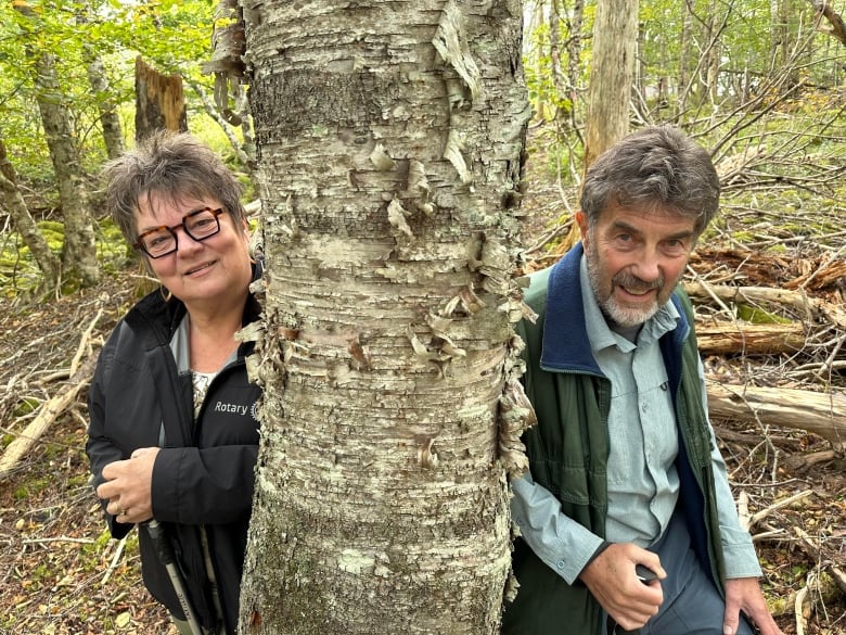 Two people are shown leaning against a birch tree.