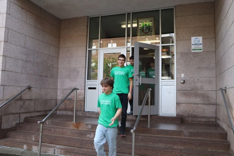 three kids in green Saint-Patrick's High School T-shirts walking out of the school.