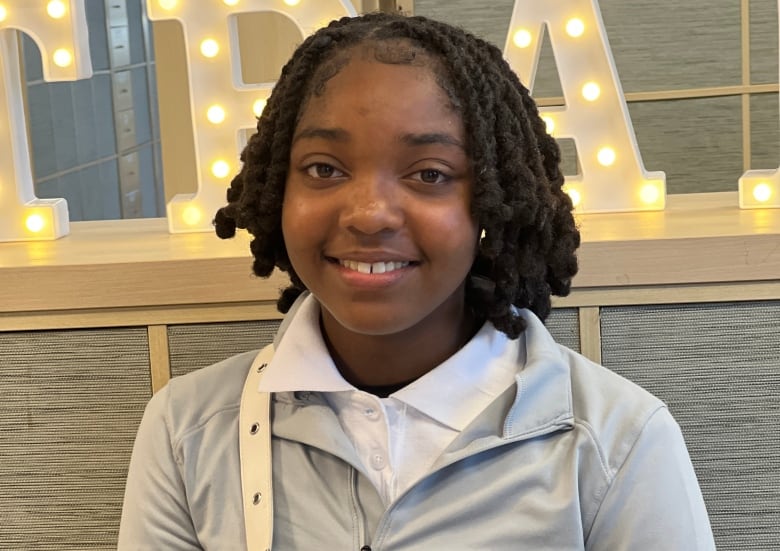 Portrait of a smiling teen with black curly hair.