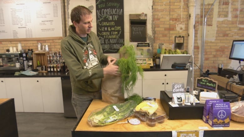 A man puts food into a paper bag.