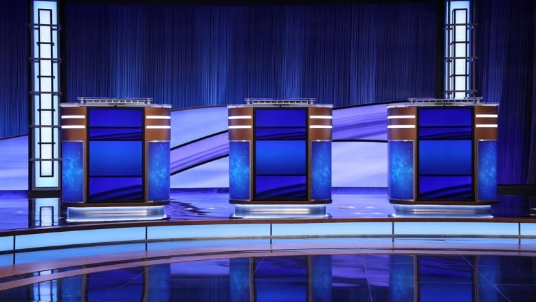  Three blue podiums are framed by a blue background with two lit pillars on either side.