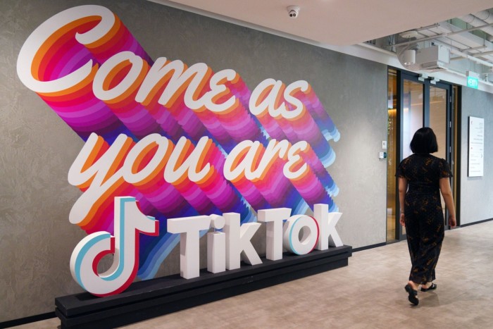 Person walks by signs outside TikTok’s offices in Singapore