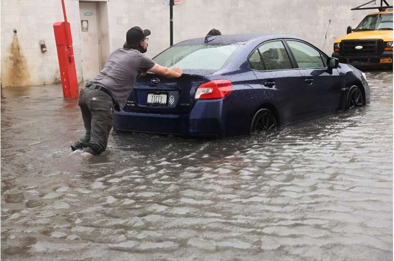 A car is pushed through flooded streets in New York's Brooklyn on September 29, 2023