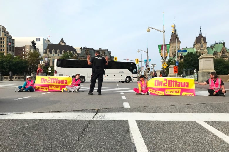 Protesters block a road as a police officer stands nearby.