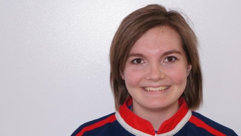 A teenage girl smiles at the camera in a rugby uniform.