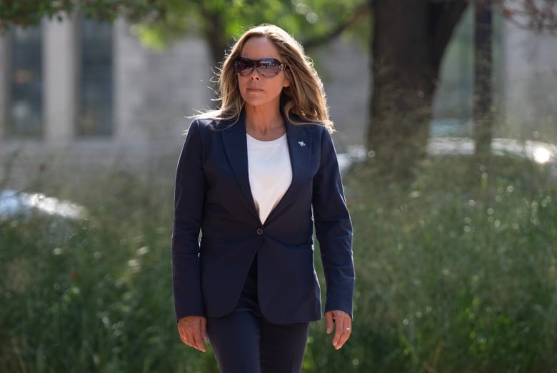 A woman walks toward a courthouse on a summer day.