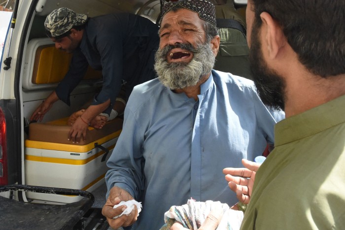 A man weeps in front of an ambulance