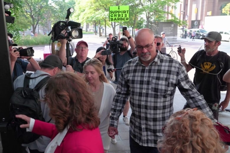 Man in a plaid shirt walks into court.