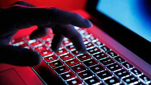 An image of a laptop keyboard, with a hand poised to type above it