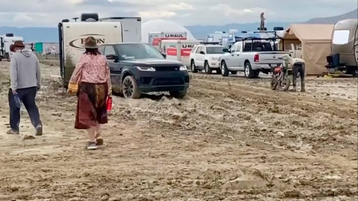 People walk through the mud at the Burning Man festival site