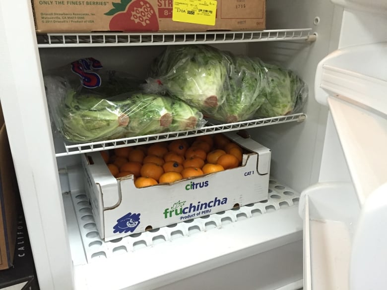 An open-door fridge with fruits and vegetables inside.