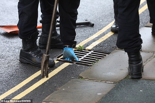 An officer searching in nearby grids after police officers cordoned off a street, in Halifax, West Yorkshire